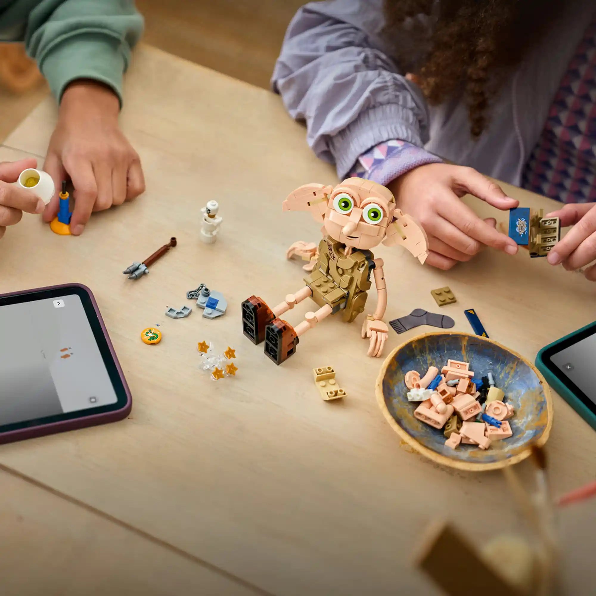 LEGO Harry Potter Dobby, a szabad manó 76469 építés közben egy asztalon, körülötte Harry Potter kiegészítők, Tom Denem naplója, lámpa és varázslatos elemek.
