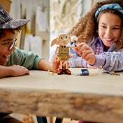 Gyerekek játszanak a LEGO Harry Potter 76469 Dobby figurával, amely mozgatható végtagokkal és ikonikus Harry Potter kiegészítőkkel van felszerelve.