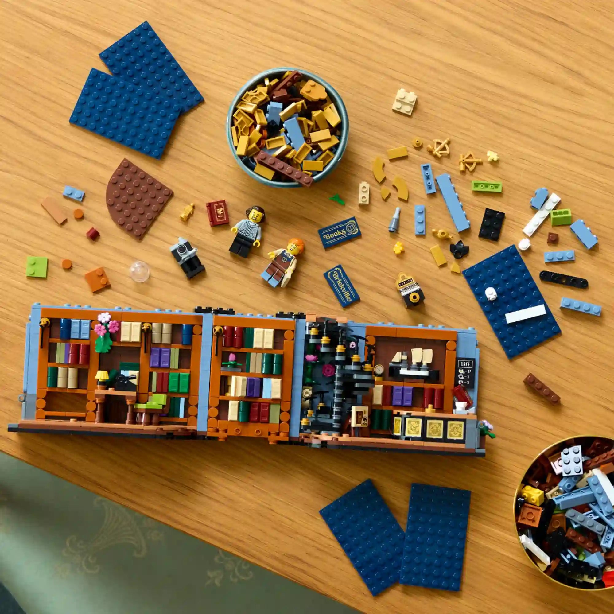 LEGO Icons (Creator Expert): Könyvkuckó Könyvesbolt 11379 építés közben, könyvespolcokkal, minifigurákkal és szétválogatott LEGO elemekkel.