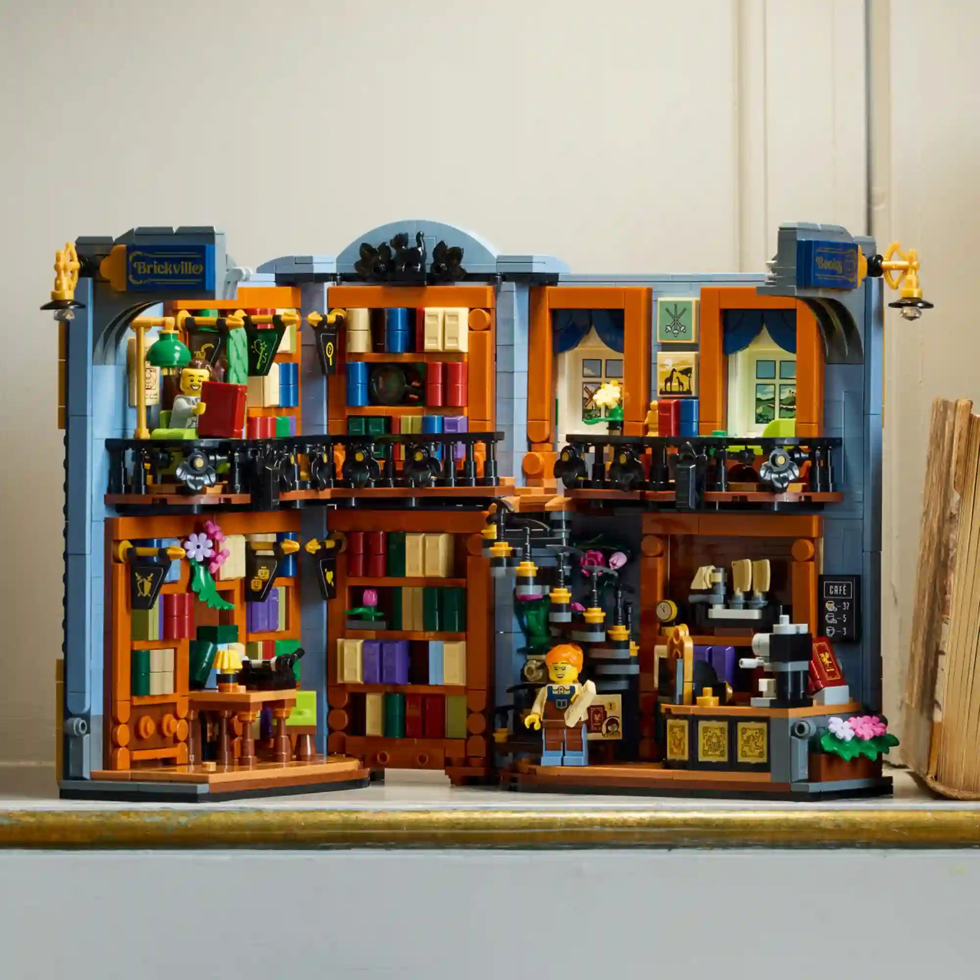 LEGO Icons (Creator Expert): Könyvkuckó Könyvesbolt 11379 összeépített modellje polcon, kétszintes könyvesbolttal, kávézóval és minifigurákkal.