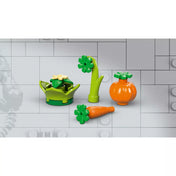 „A LEGO 76962 készlet zöldségkiegészítői: tök, répa, virágos növény és salátalevél elem, világos szürke LEGO háttér előtt lefotózva.”