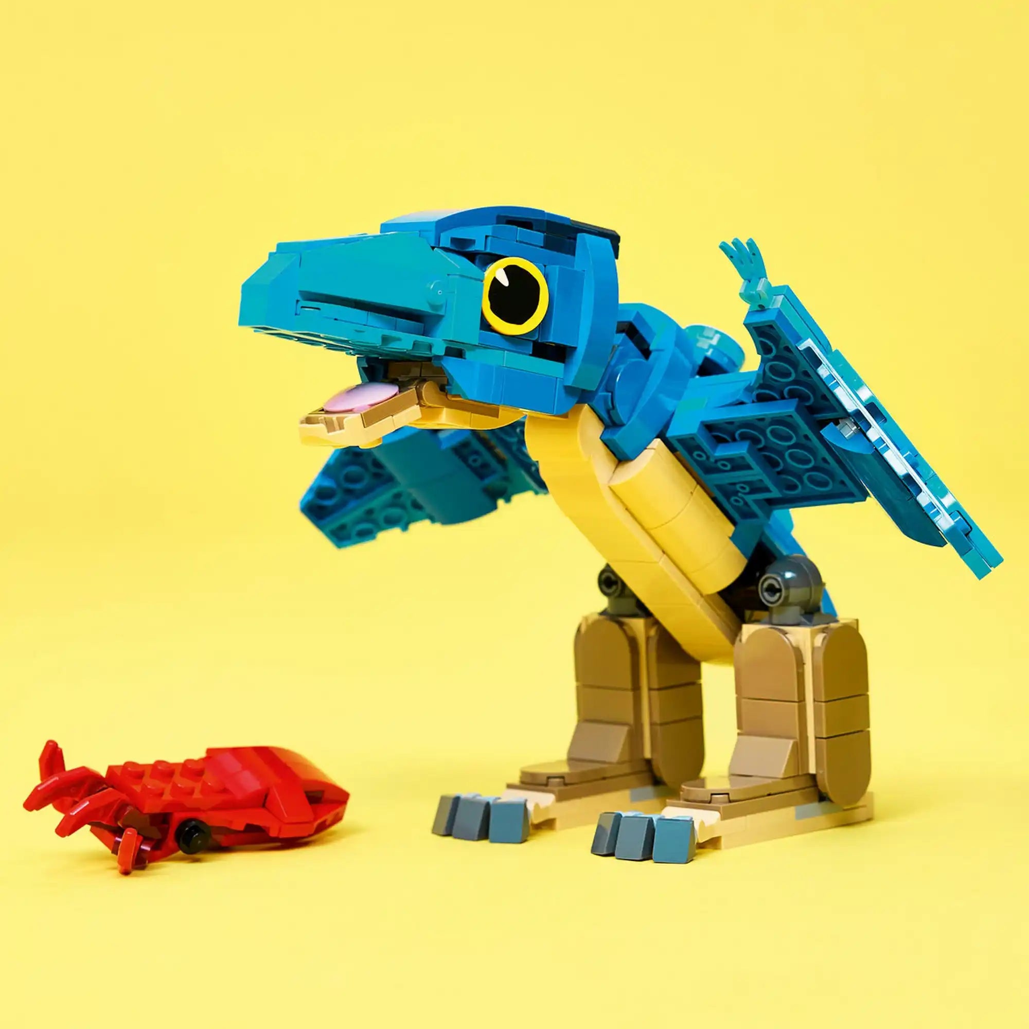 Kiállított modell: LEGO Jurassic World Bébi pteranodon figura nyitott csőrrel és piros tintahallal sárga háttér előtt.