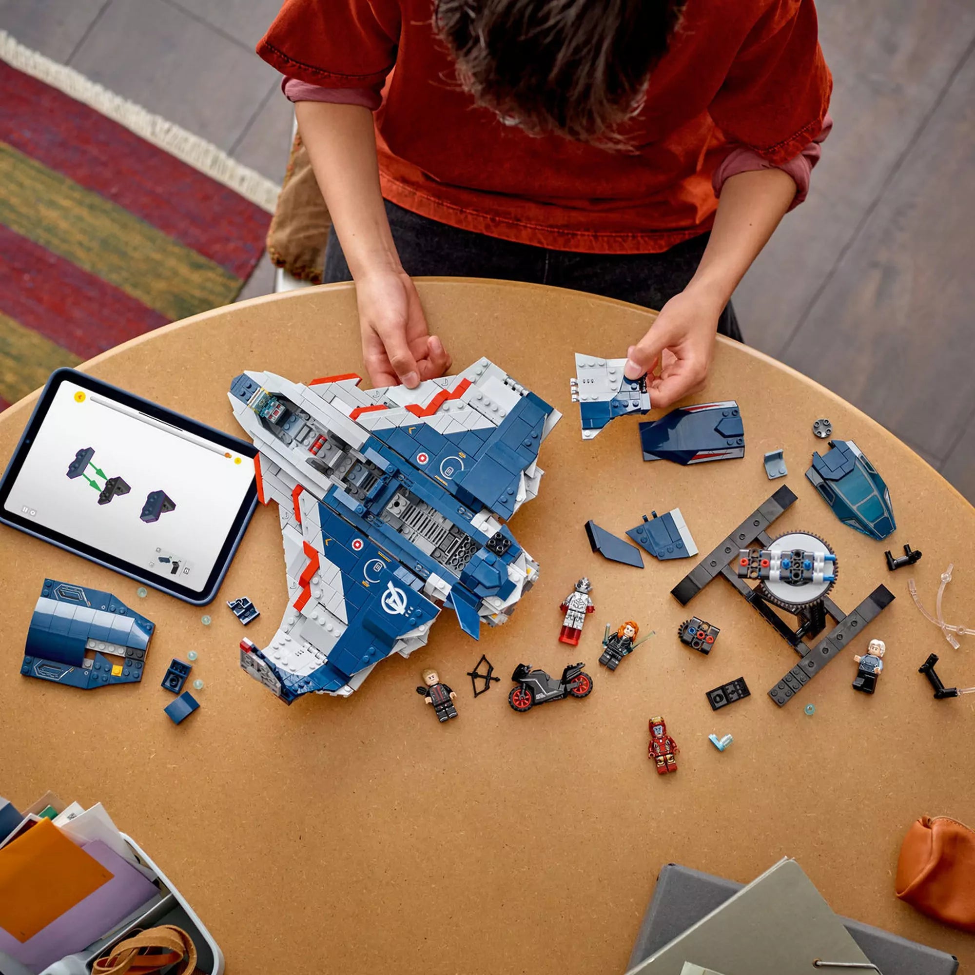  Gyerek építi a LEGO Marvel Quinjet (76325) repülőgépet, szétszórt elemekkel, minifigurákkal és tableten megjelenő digitális útmutatóval.