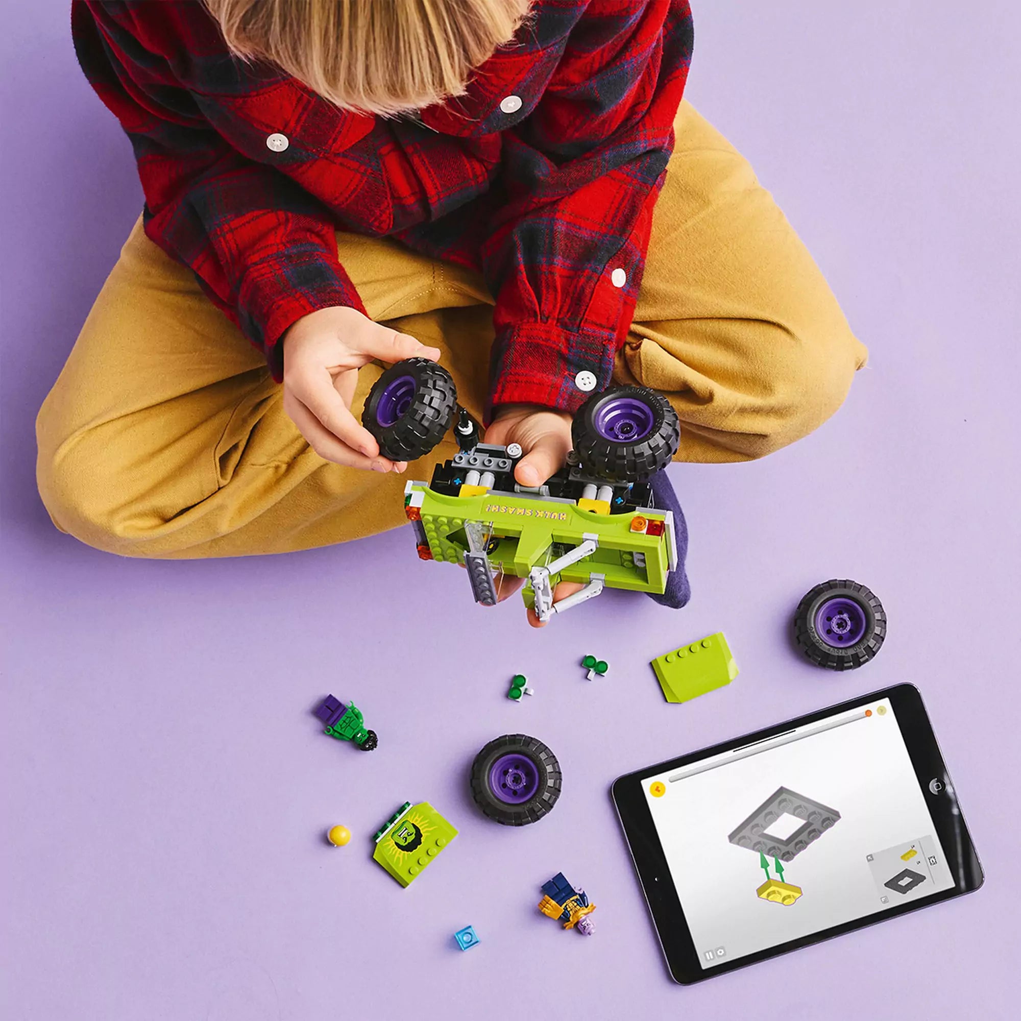 Egy gyermek a LEGO Marvel Hulk óriási terepjárója vs. Thanos készletet szereli egy tableten futó digitális útmutató segítségével.