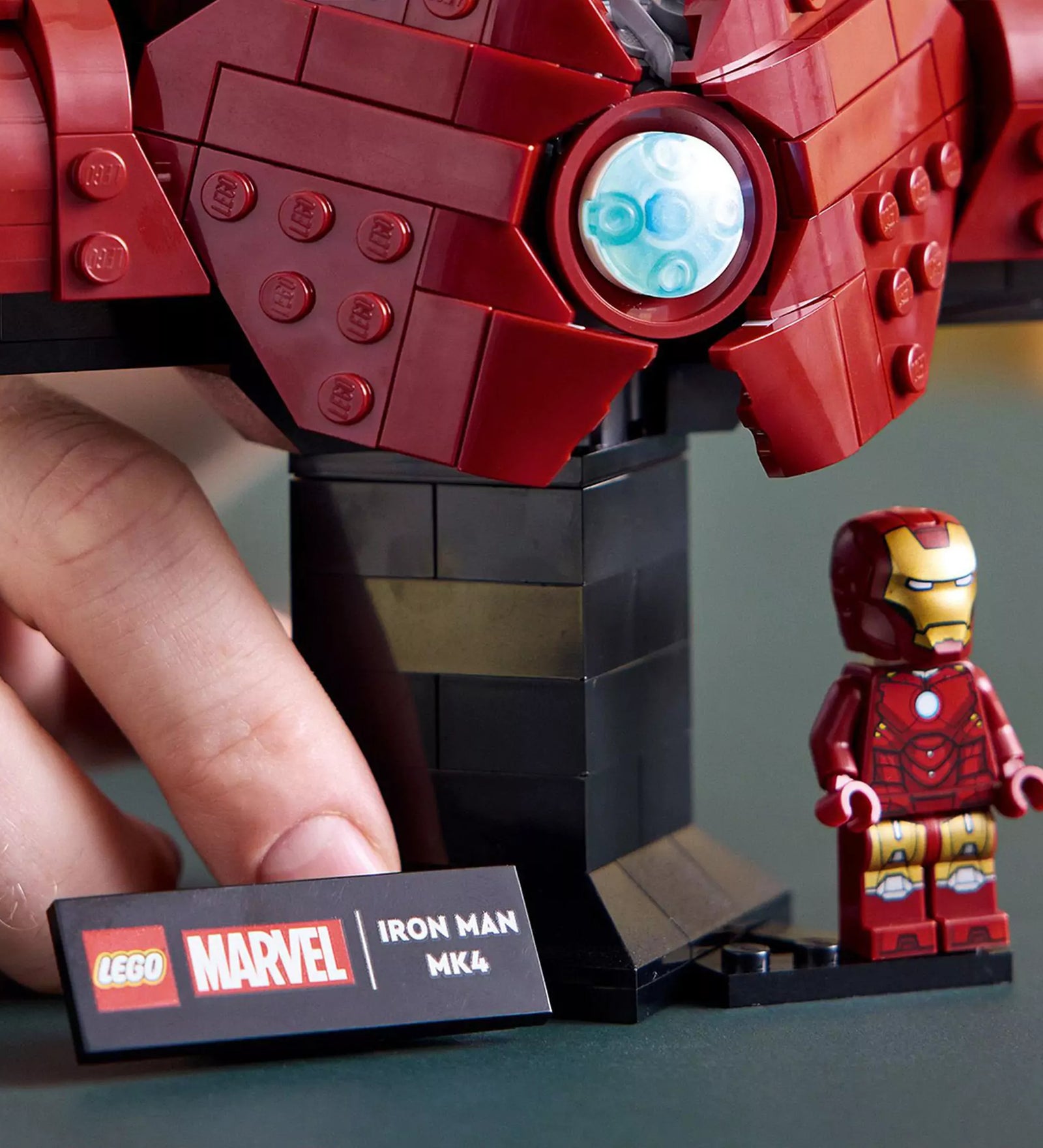 A LEGO Marvel Iron Man MK4 mellszobor (76327) talapzata közelről, előtte az információs tábla és egy klasszikus Iron Man minifigura.