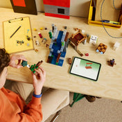 Gyermek építi a LEGO Minecraft Szellemkikötő (21597) készletet, miközben a LEGO Builder alkalmazás digitális útmutatója segíti az összeszerelést.