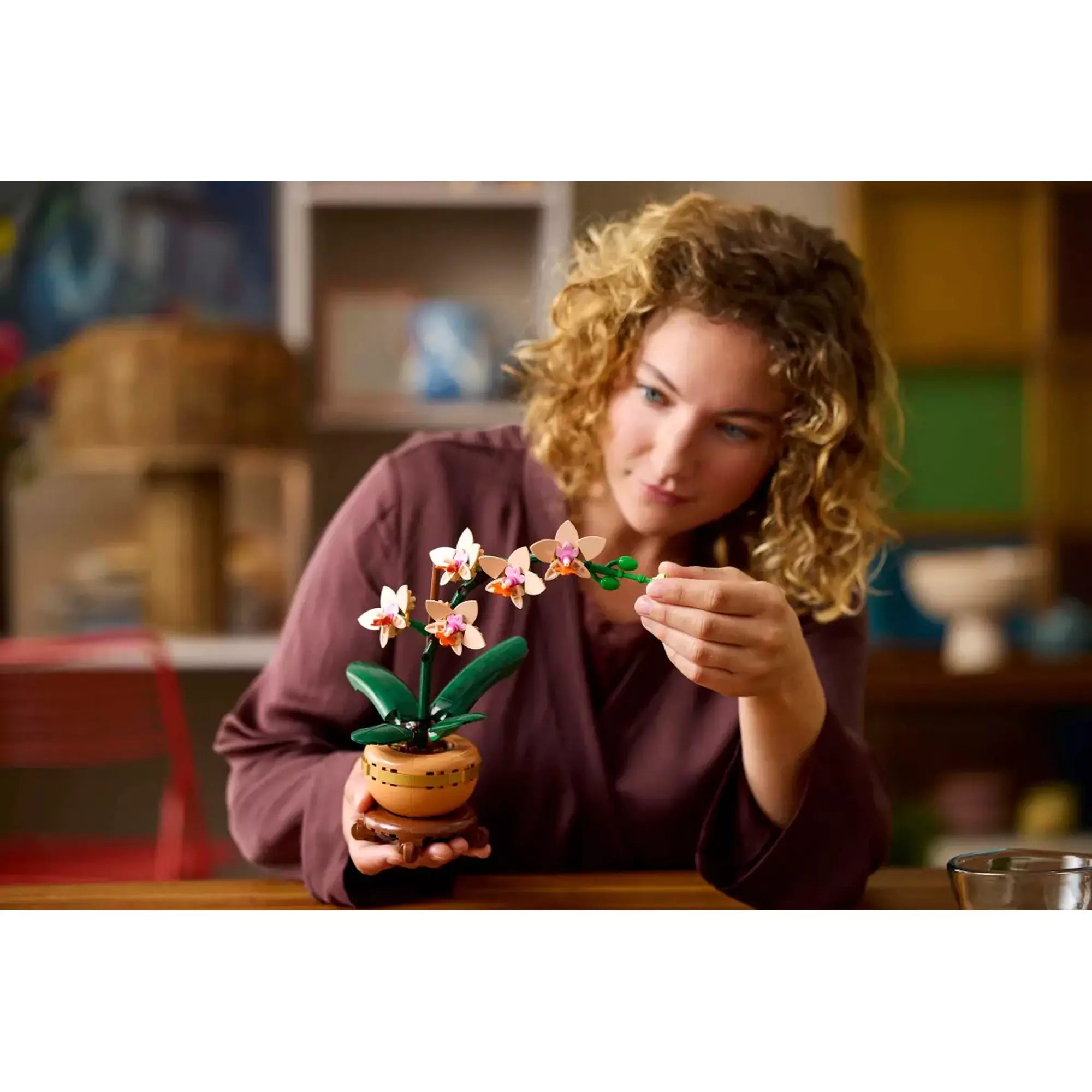 Egy személy a LEGO Botanicals 'Mini Orchid' készletet építi, kiemelve a készlet kreatív jellemzőit