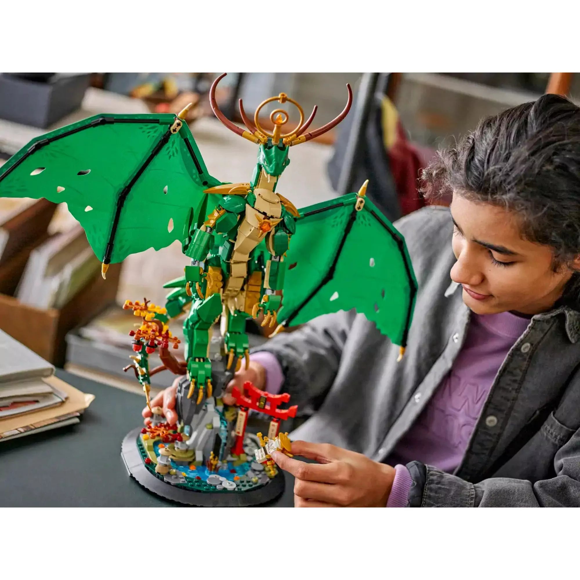 Egy gyermek játszik a LEGO NINJAGO Az Őrsárkány (71847) készlettel, miközben a lenyűgöző sárkányfigurát és a részletgazdag alapot vizsgálja.
