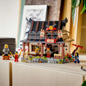 LEGO NINJAGO: Négy Fegyver Kovácsműhely, 15. évforduló készlet megépített kovácsház épülettel és minifigurákkal kiállítva polcon.