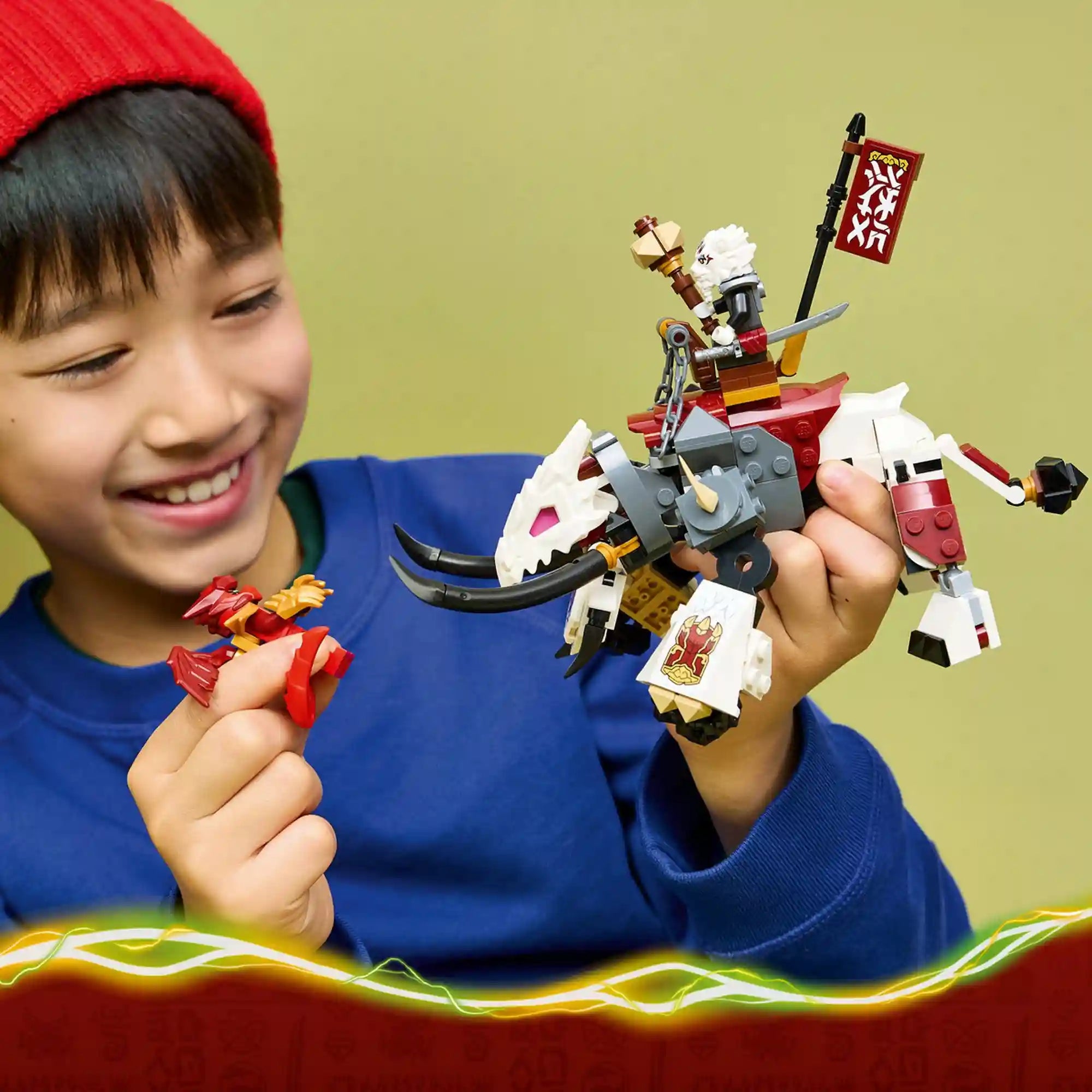 Gyermek kezében a LEGO NINJAGO Grimtak sárkányszörny modell, mellette Kai sárkányformájú minifigura, részletgazdag fantasy harci jelenet.