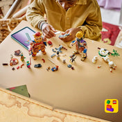 Gyermek építi a LEGO ONE PIECE Dorry vs. Brogy – A Kicsi Kert óriásai 75644 készletet, miközben az óriásfigurák és a minifigurák az asztalon láthatók.