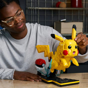 LEGO Pokémon: Pikachu és pokélabda 72152, 2050 darabos életkép, ahol egy felnőtt építi és bemutatja a kész Pikachu modellt asztalon.