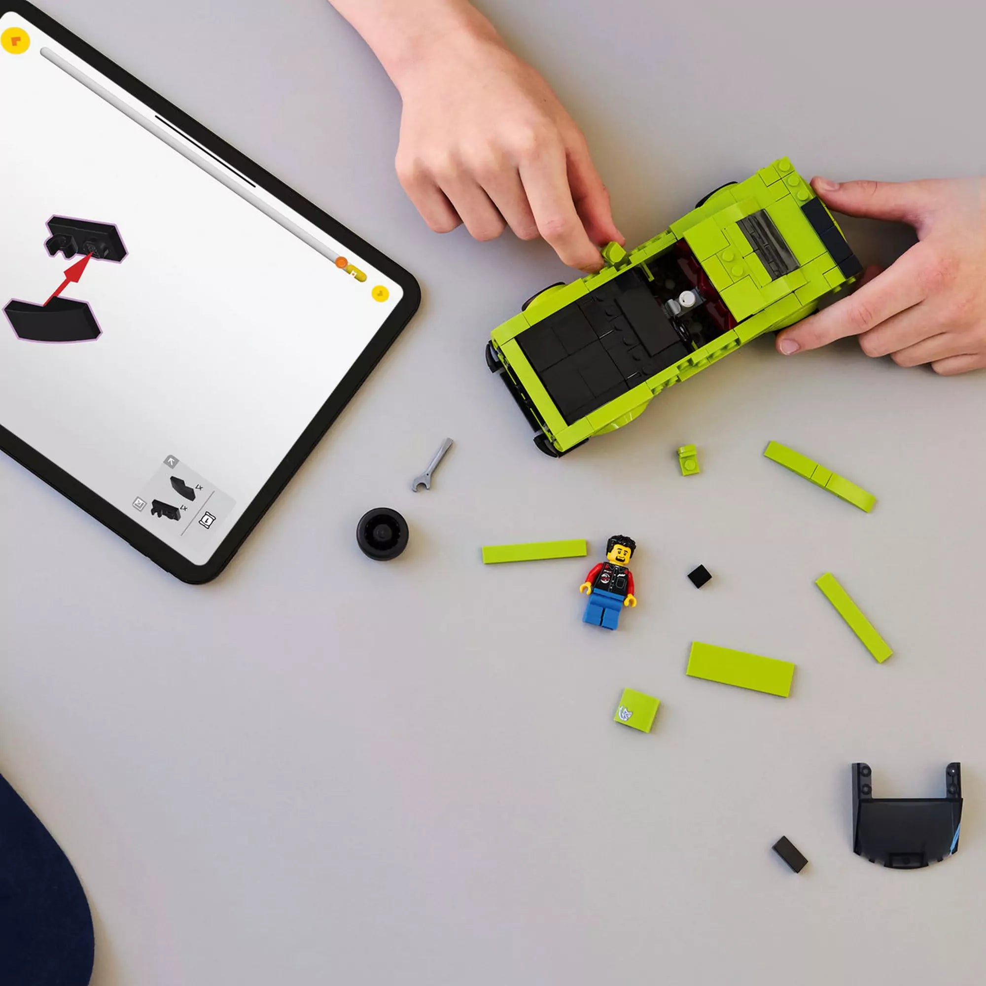 Gyerek építi a LEGO Dodge Challenger SRT Hellcat (77237) autót, tableten digitális útmutatóval és szétszórt elemekkel.
