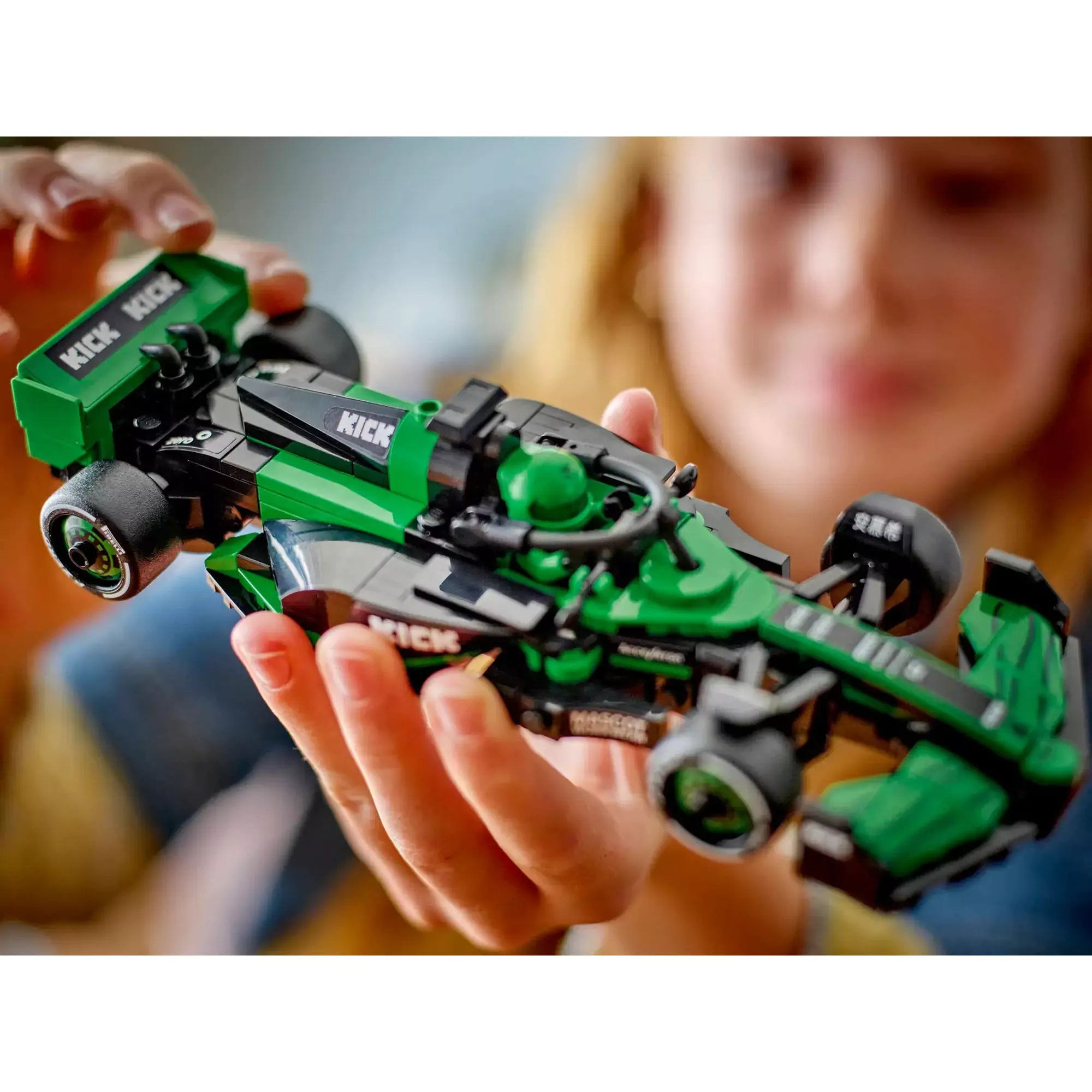Lány kézben tartja a részletesen kidolgozott LEGO KICK Sauber F1 Team C44 autót.