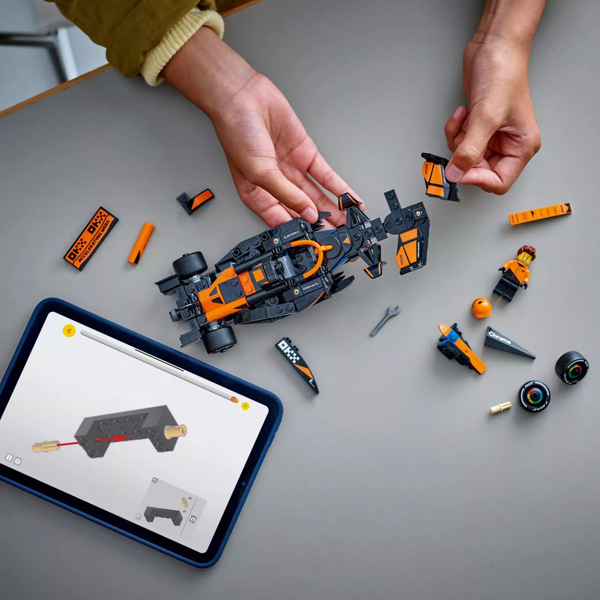 LEGO Speed Champions McLaren F1 Team MCL38 versenyautó építése közben, tableten megjelenített digitális útmutatóval.
