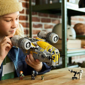 LEGO Star Wars 75447 The Razor Crest űrhajó játék közben, gyermek kezében, minifigurákkal az asztalon.