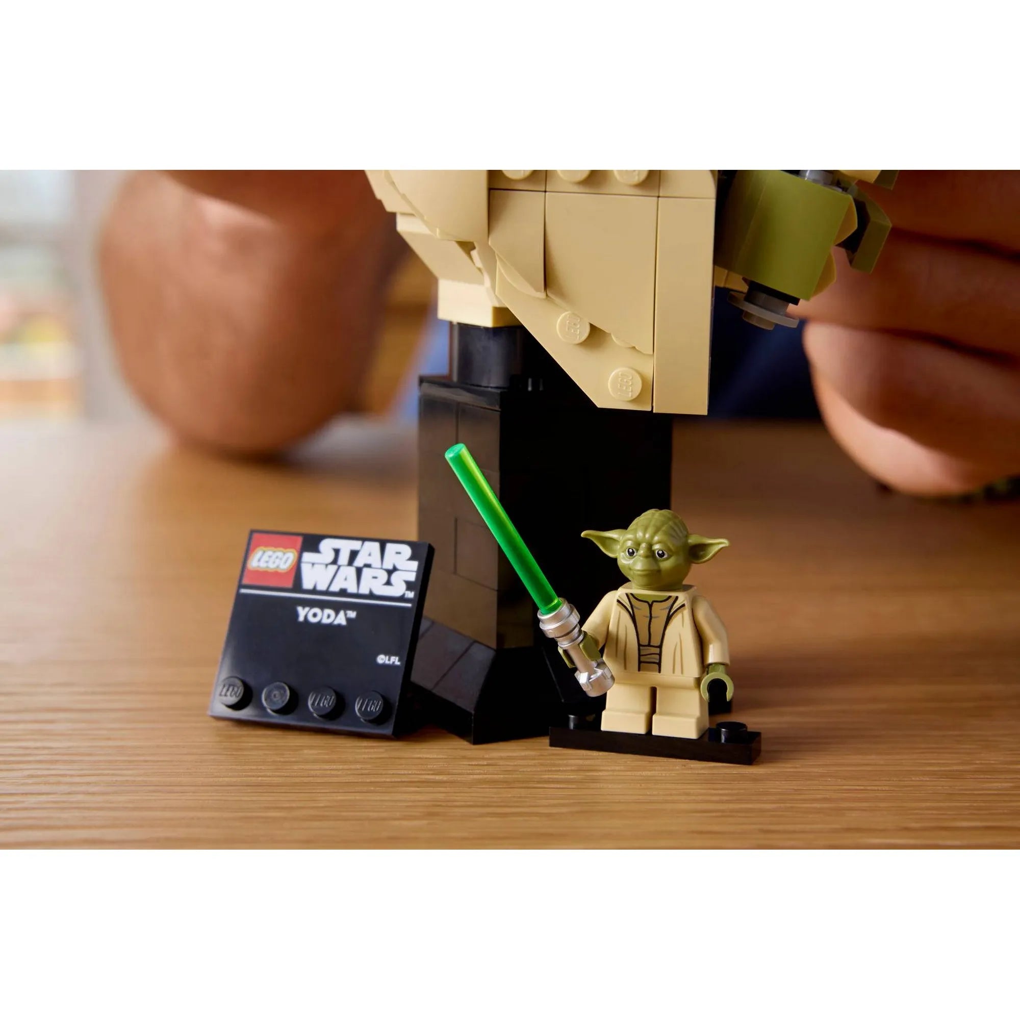 LEGO Star Wars Yoda mellszobor talapzata névtáblával és minifigurával, közelről fotózva.