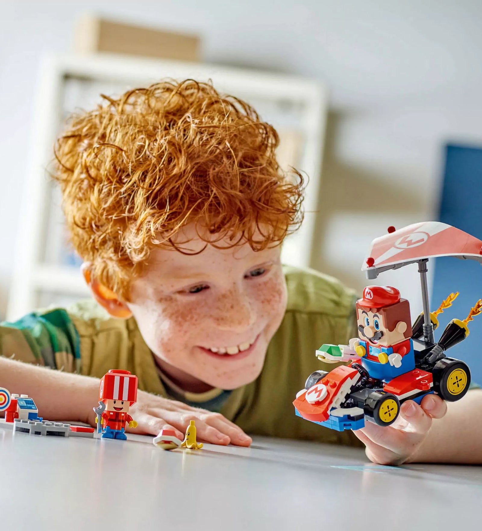 Egy boldog gyerek a készre épített LEGO Super Mario Mario Kart, Standard Kart 72032 járművel játszik.