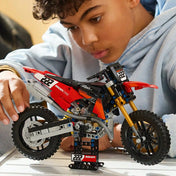 A LEGO Technic: Ducati Desmo450 MX Factory motorkerékpár 42238 modellt egy gyermek játék közben forgatja.