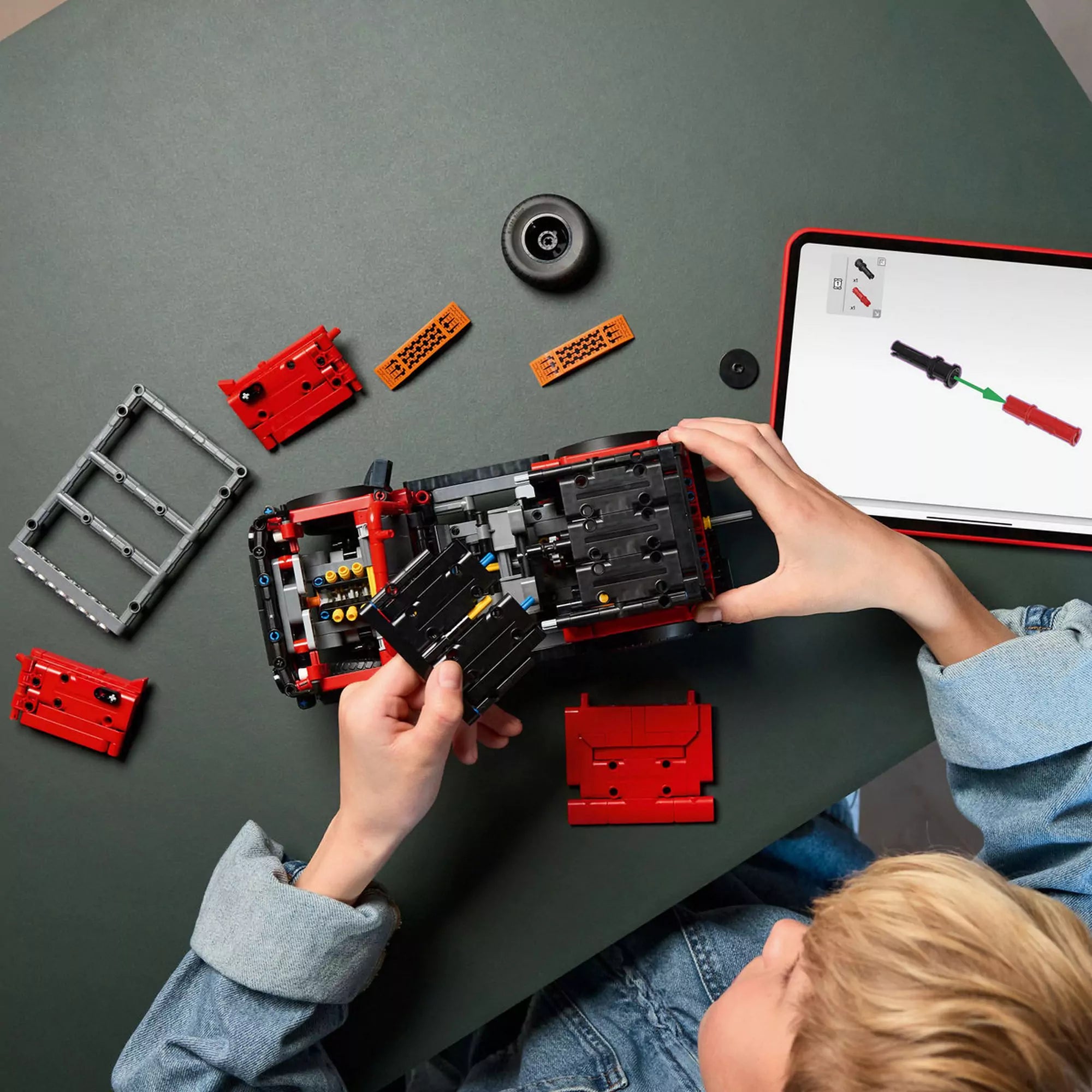 LEGO Technic Ford Bronco SUV (42213) építés közben – Gyermek rakja össze a terepjárót, mellette tableten látható 3D-s LEGO útmutató.
