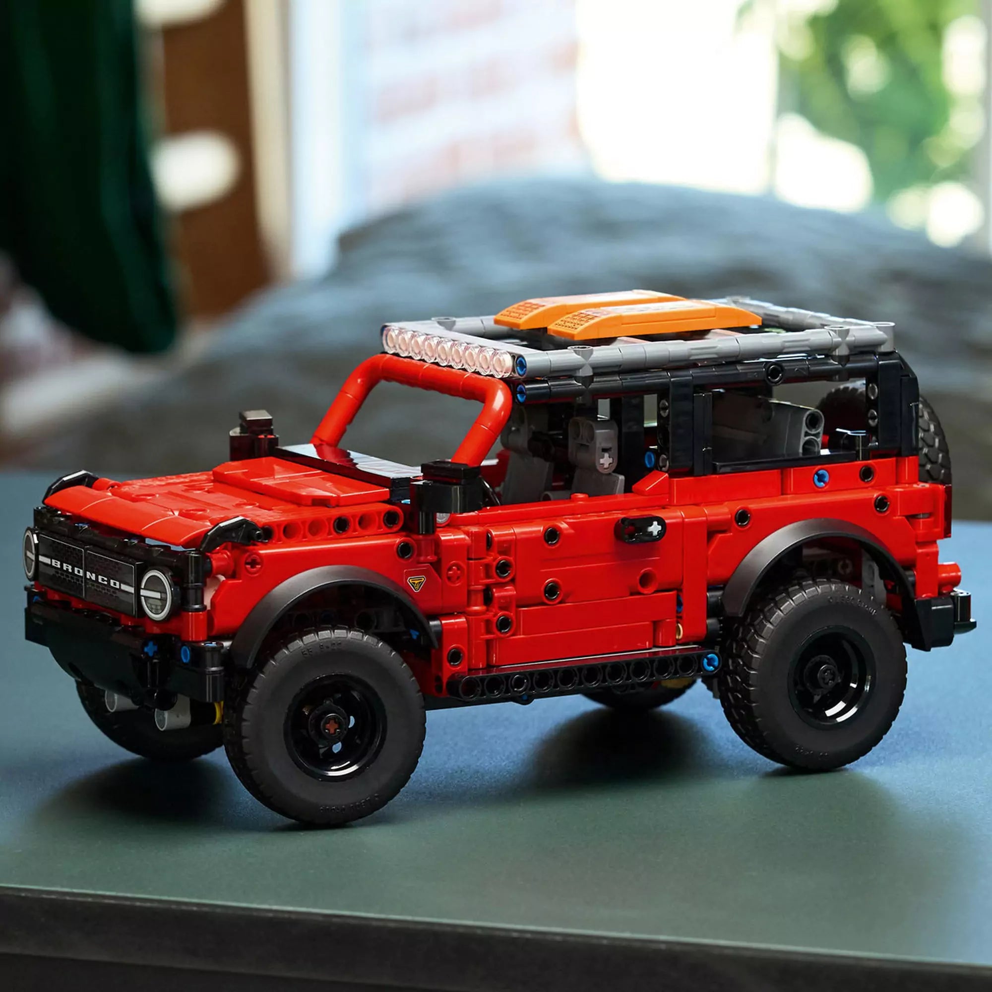 LEGO Technic Ford Bronco SUV (42213) kiállítva asztalon – Az elkészült piros-fekete terepjáró beltéri háttérben, részletes tetőcsomagtartóval.