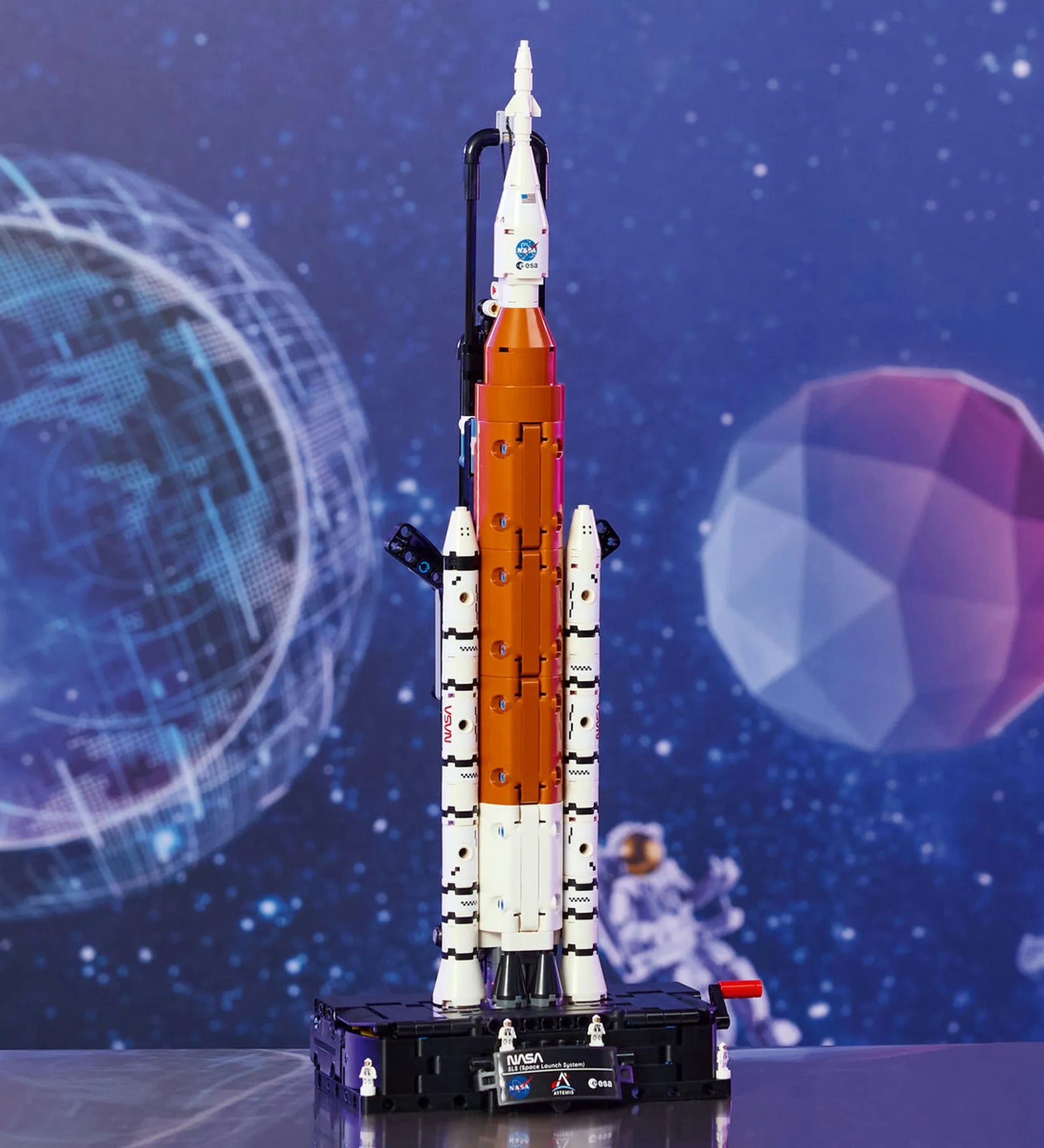 LEGO Technic: NASA Artemis rakétakilövő rendszer 42221 – Megépített Artemis rakéta kiállító talapzaton, űr témájú háttér előtt.