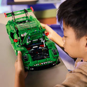 Gyermek LEGO Technic Porsche 911 GT3 R REXY AO Racing autóval játszik, nyitott motorházzal és látható mechanikus részletekkel