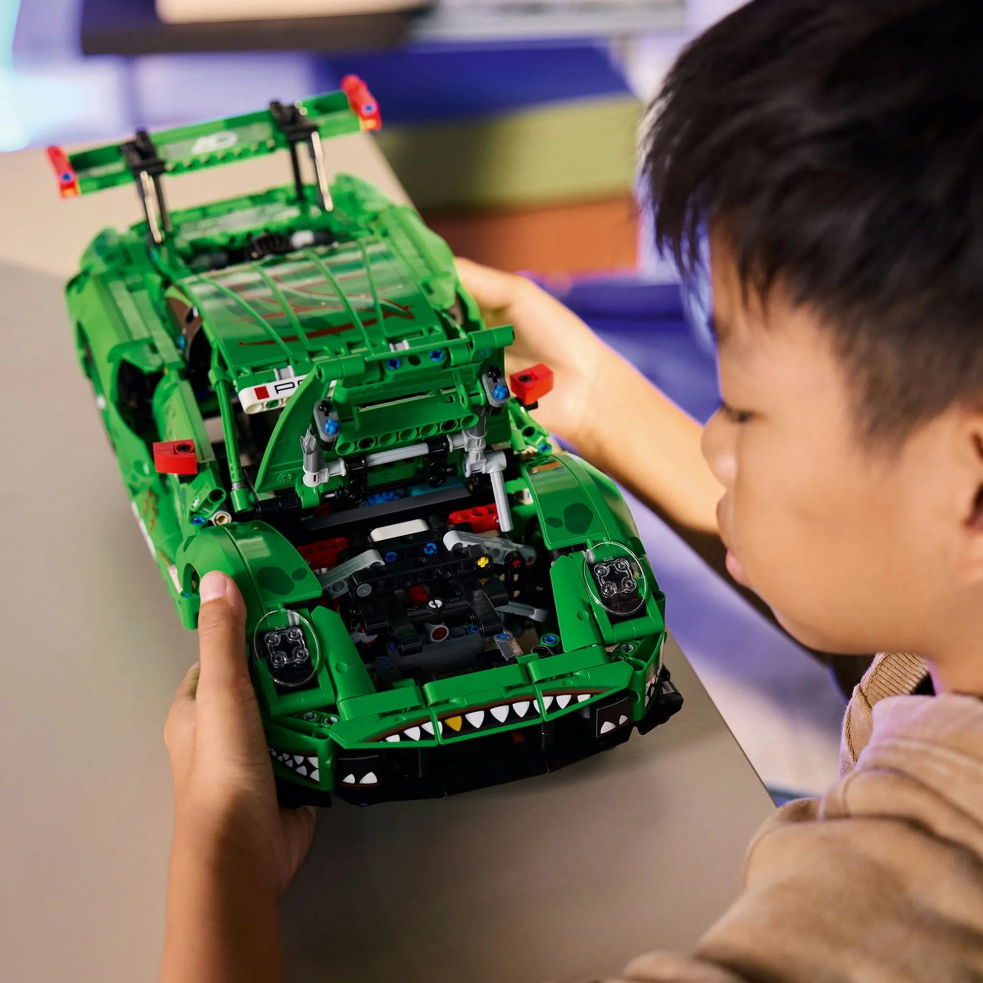 Gyermek LEGO Technic Porsche 911 GT3 R REXY AO Racing autóval játszik, nyitott motorházzal és látható mechanikus részletekkel