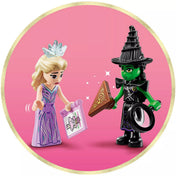 A LEGO Wicked – Emerald City & Kiamo Ko Castle (75689) két figurája: Glinda és Elphaba, kiegészítőkkel rózsaszín háttér előtt.