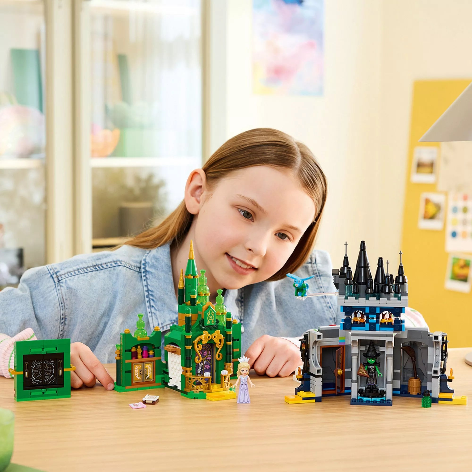 Gyermek játszik a LEGO Wicked – Emerald City & Kiamo Ko Castle (75689) Smaragdváros és kastély modelljeivel.