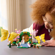 Gyerek játszik a LEGO Wicked: Glinda esküvője (75688) készlettel, a pillangókkal díszített zöld kapu előtt.