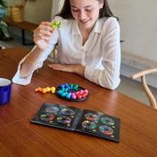 IQ Circle logikai játék használat közben, játékos színes elemeket helyez a játéktáblára a feladványfüzet alapján.