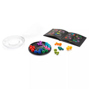 A Smart Games IQ Deluxe Circle készlet tartalma: átlátszó fedél, fekete kör alakú játéktábla, több színes műanyag puzzle-elem és egy kihívásfüzet különböző nehézségi szintekkel. A fotó bemutatja, hogyan épül fel a játék a logikai feladványok megoldása közben.