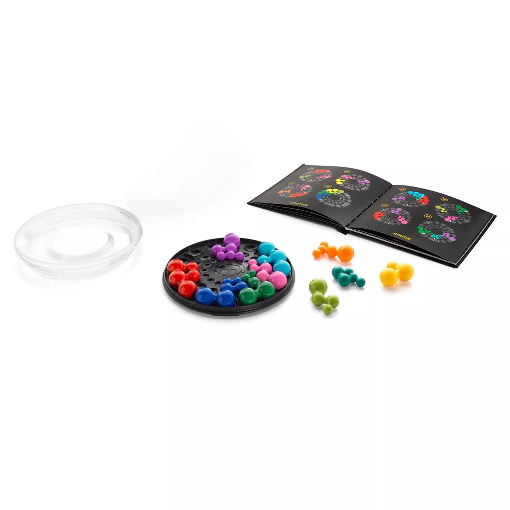 A Smart Games IQ Deluxe Circle készlet tartalma: átlátszó fedél, fekete kör alakú játéktábla, több színes műanyag puzzle-elem és egy kihívásfüzet különböző nehézségi szintekkel. A fotó bemutatja, hogyan épül fel a játék a logikai feladványok megoldása közben.
