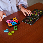 IQ Square logikai játék használat közben, kirakóelemek és kihívásfüzet az asztalon.